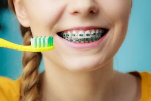 Young girl with braces brushing her teeth